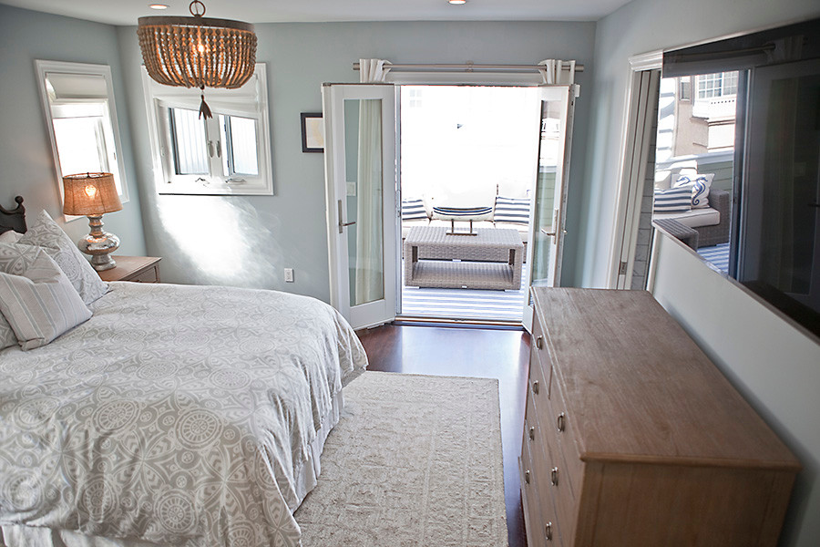 This is an example of a medium sized nautical master bedroom in San Diego with blue walls and dark hardwood flooring.