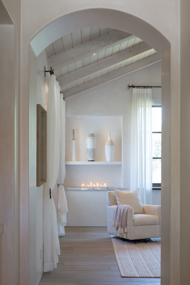 Inspiration pour une grande chambre parentale méditerranéenne avec un mur blanc, une cheminée ribbon, parquet clair et un sol marron.