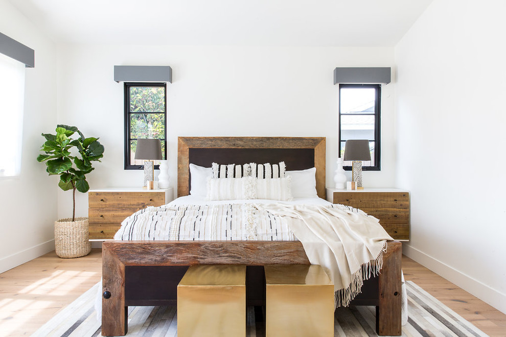 Modelo de dormitorio principal de estilo de casa de campo grande sin chimenea con paredes blancas y suelo de madera clara