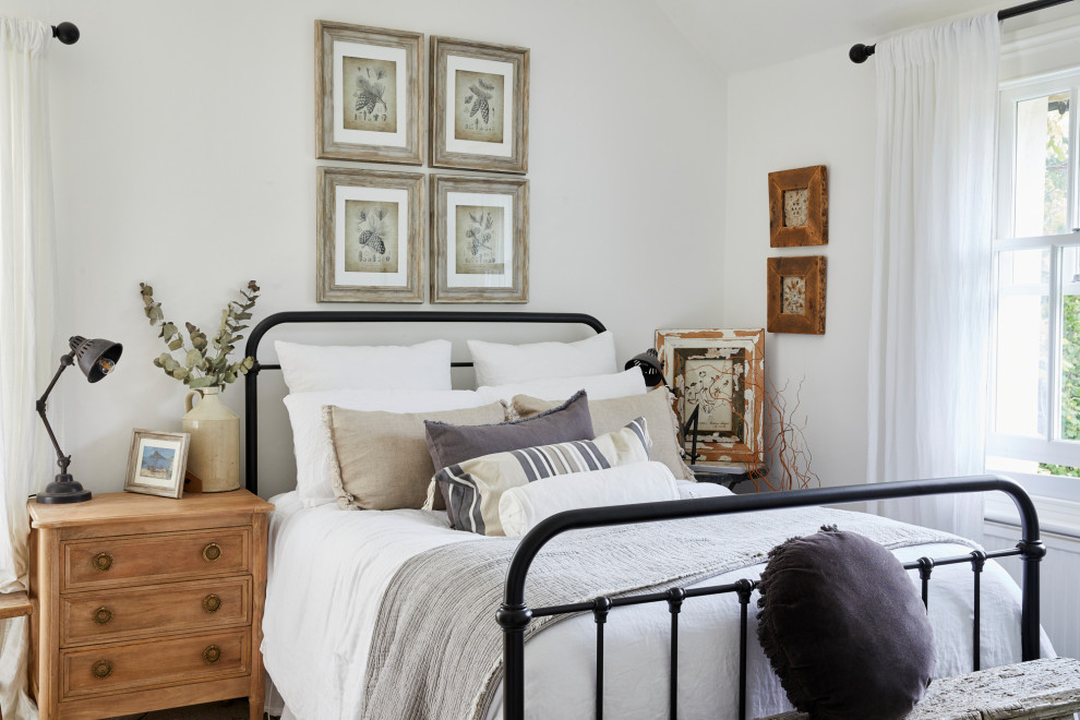 This is an example of a coastal guest bedroom in London with white walls and no fireplace.