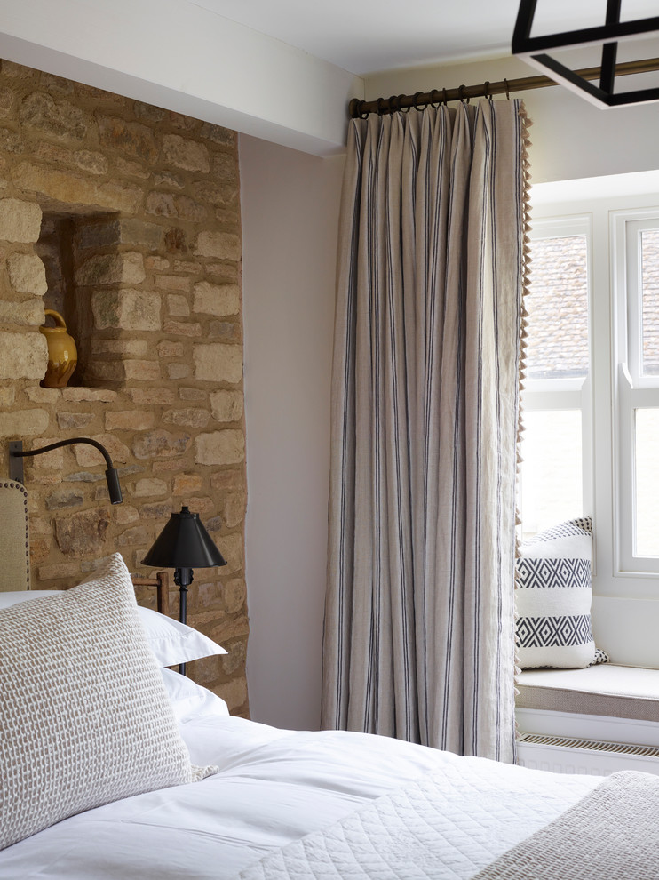 This is an example of a small rural master bedroom in Oxfordshire with white walls.