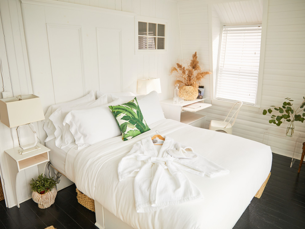 На фото: хозяйская спальня среднего размера в морском стиле с белыми стенами, деревянным полом и черным полом с