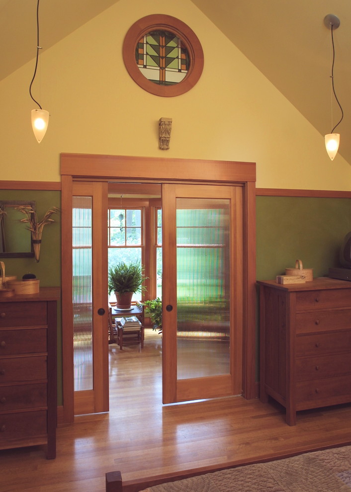 Idées déco pour une chambre parentale craftsman de taille moyenne avec un mur vert et un sol en bois brun.
