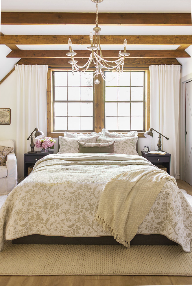 Modelo de dormitorio principal de estilo de casa de campo de tamaño medio con paredes blancas, suelo laminado y suelo marrón