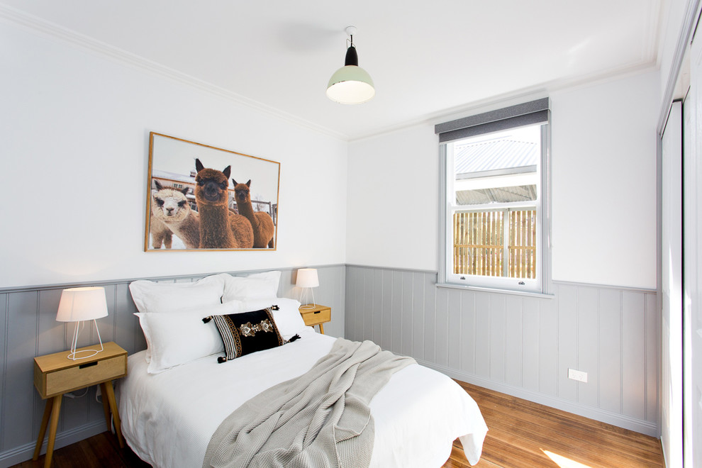 Foto de dormitorio nórdico con paredes blancas, suelo de madera en tonos medios y suelo marrón