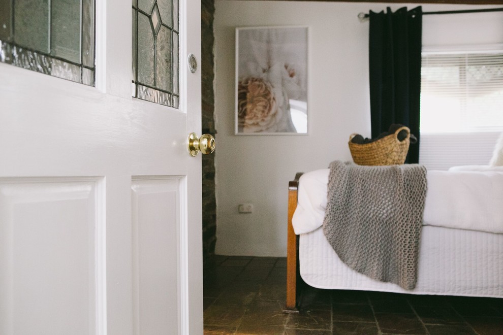 Foto de dormitorio campestre pequeño con paredes blancas, suelo de pizarra y estufa de leña