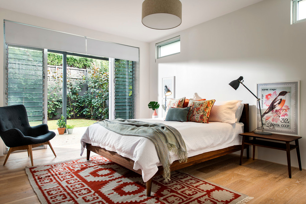 Ejemplo de dormitorio retro de tamaño medio con paredes blancas y suelo de madera clara
