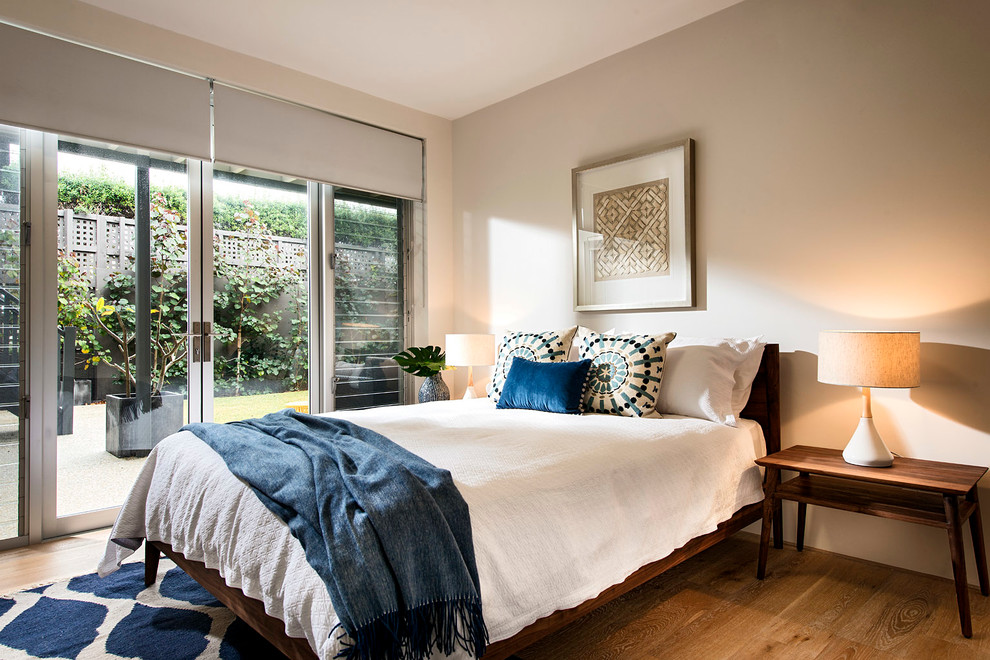 Diseño de dormitorio retro con paredes beige y suelo de madera en tonos medios
