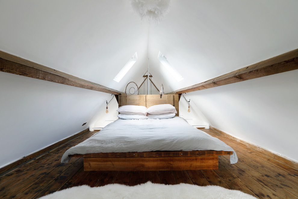 Diseño de dormitorio tipo loft rural pequeño con paredes blancas, suelo de madera oscura y techo inclinado
