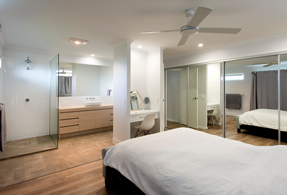 Modelo de dormitorio principal minimalista de tamaño medio con paredes blancas, suelo vinílico y suelo marrón