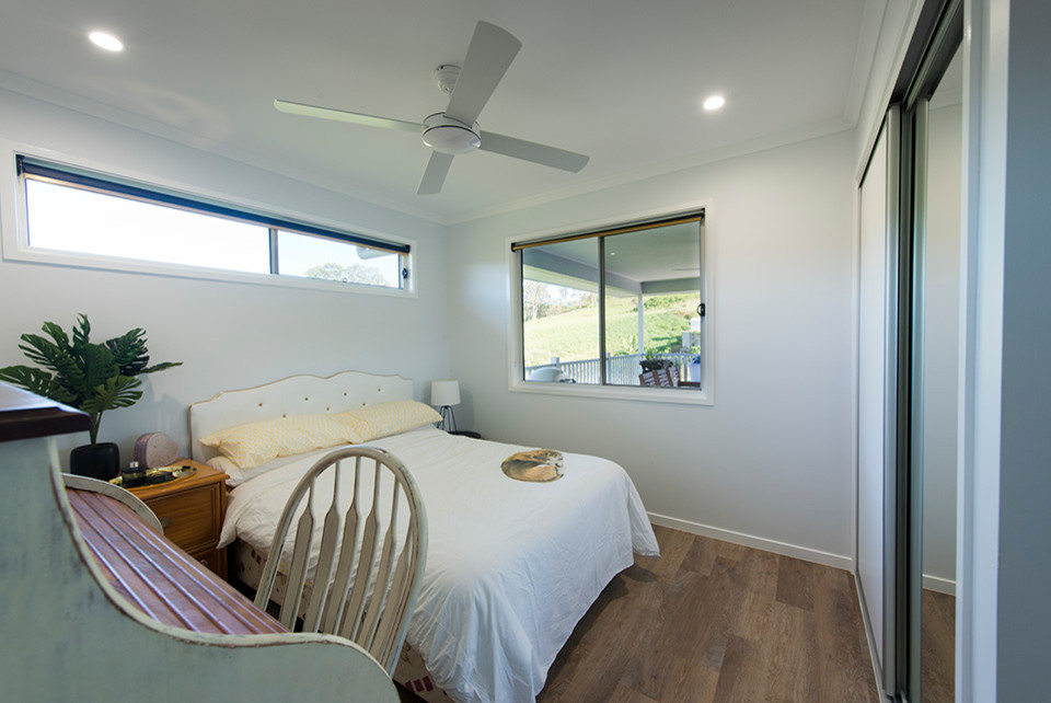 Modelo de habitación de invitados romántica de tamaño medio con paredes blancas, suelo vinílico y suelo marrón