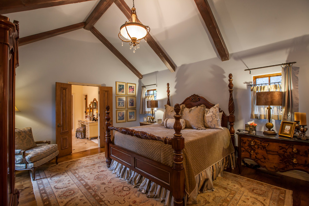 Modelo de dormitorio principal tradicional grande con paredes grises y suelo de madera en tonos medios