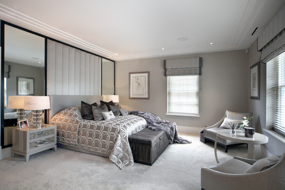 Large contemporary master bedroom in Kent with beige walls and carpet.