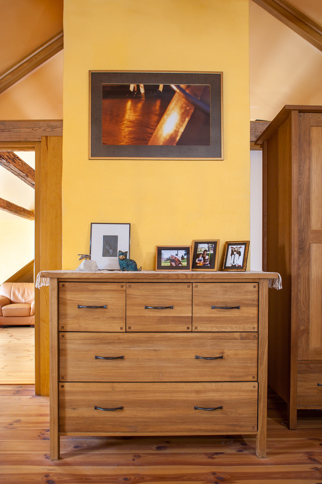 Foto de dormitorio principal campestre grande con paredes amarillas y suelo de madera clara