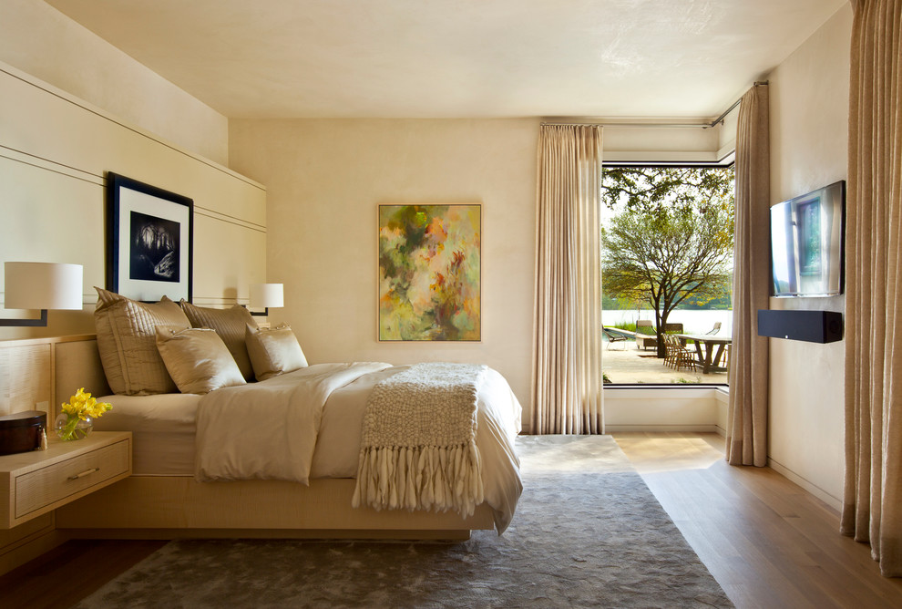 Modelo de dormitorio actual con paredes beige y suelo de madera en tonos medios