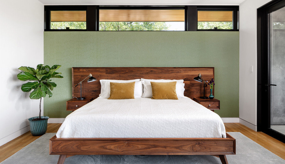 Bild på ett funkis sovrum, med gröna väggar, mellanmörkt trägolv och brunt golv