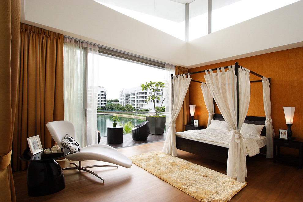 Modelo de habitación de invitados contemporánea grande con parades naranjas y suelo de madera en tonos medios