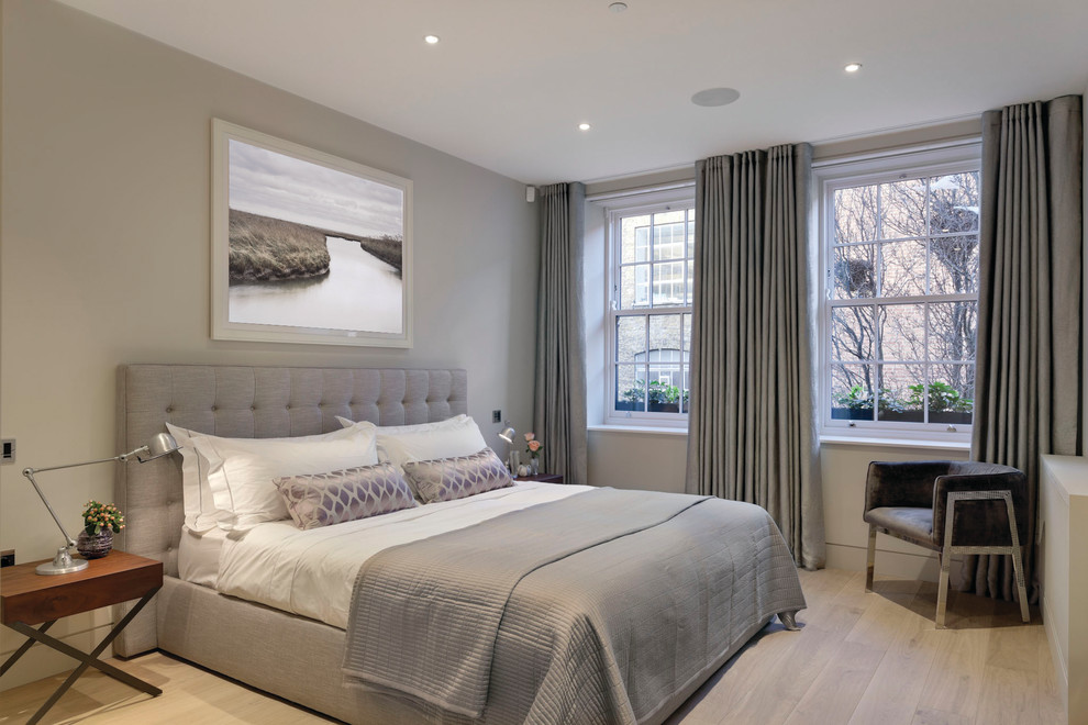 Immagine di una camera degli ospiti minimalista di medie dimensioni con pareti beige, parquet chiaro, camino sospeso e pavimento beige