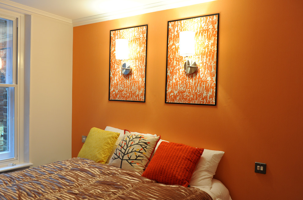 Mid-sized minimalist master carpeted bedroom photo in London with orange walls