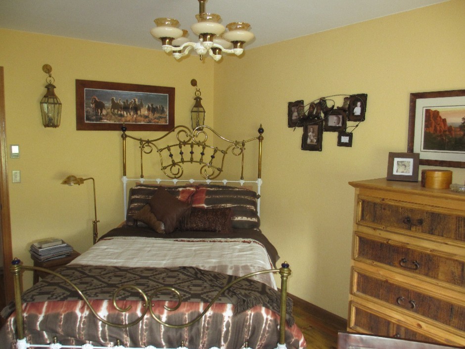 デンバーにある小さなサンタフェスタイルのおしゃれな客用寝室 (黄色い壁、無垢フローリング、ベージュの床)