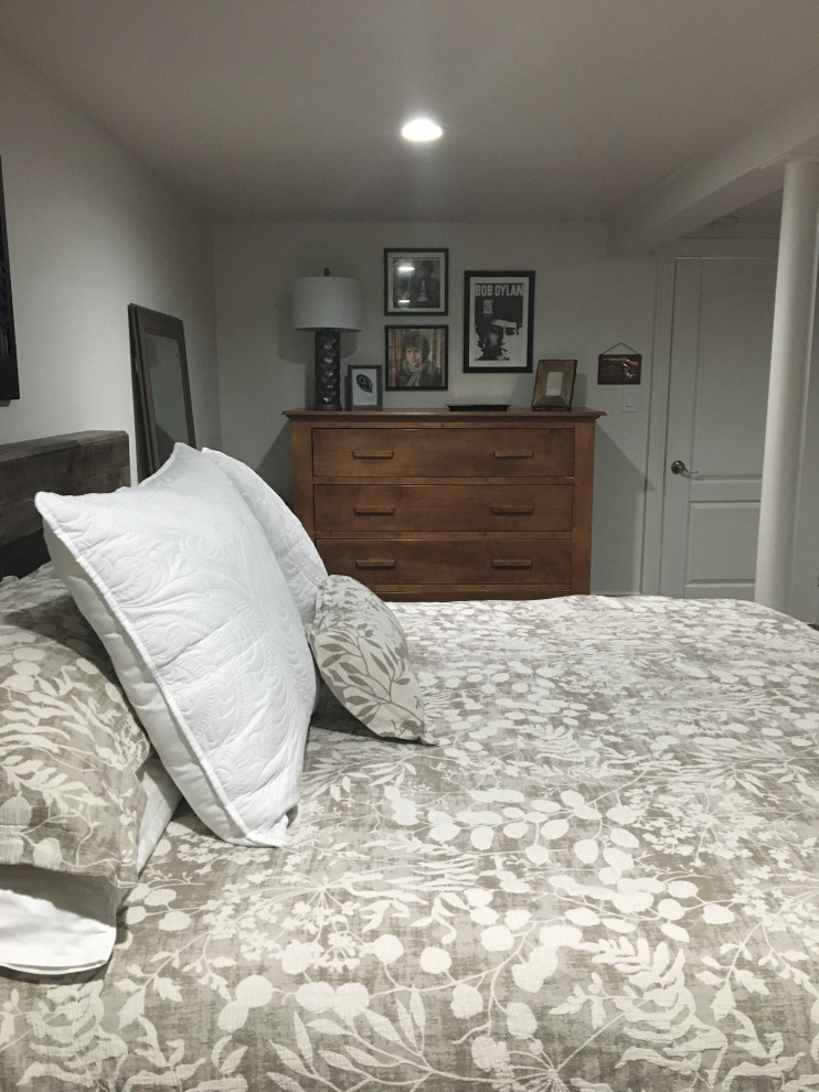 Imagen de dormitorio principal rural de tamaño medio con paredes blancas, suelo laminado y suelo marrón