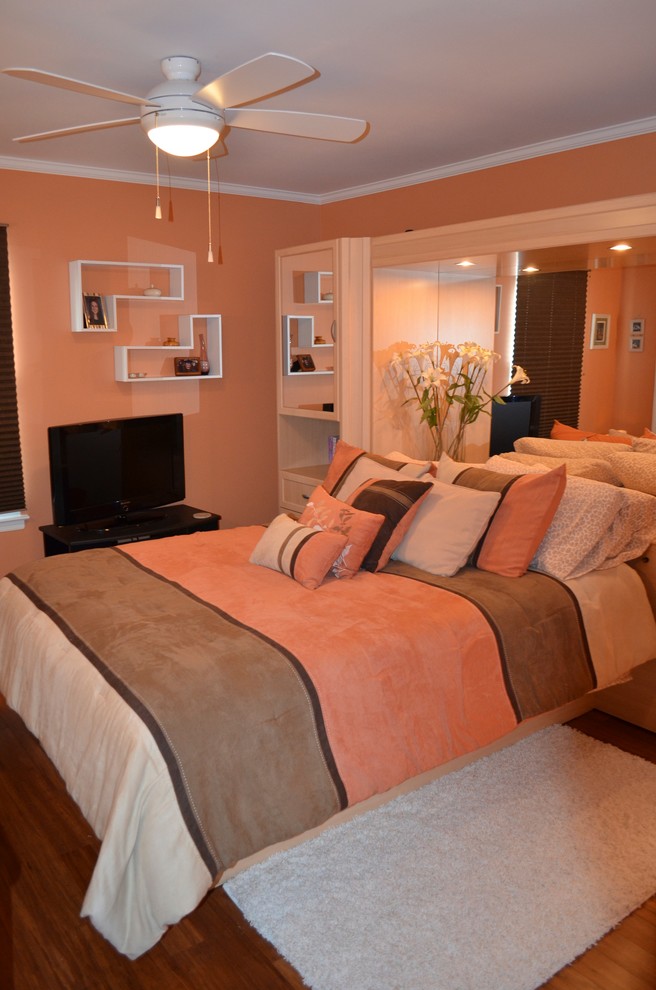 Modelo de dormitorio principal tradicional renovado de tamaño medio sin chimenea con parades naranjas y suelo de madera oscura