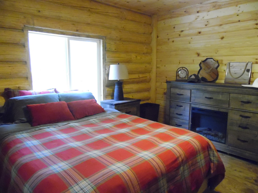 Cette image montre une petite chambre parentale chalet avec un mur beige et un sol en bois brun.
