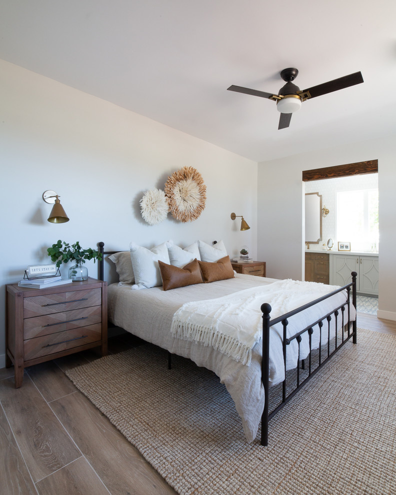 フェニックスにある中くらいなカントリー風のおしゃれな主寝室 (白い壁、磁器タイルの床、コーナー設置型暖炉、レンガの暖炉まわり、ベージュの床)