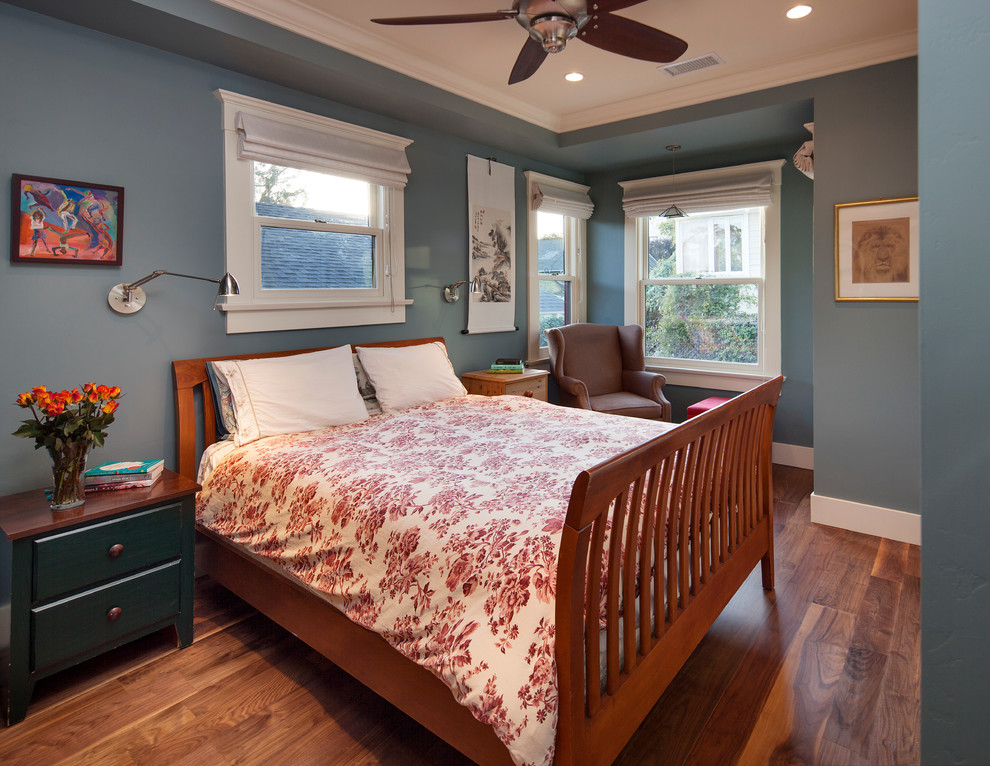 Idée de décoration pour une chambre parentale craftsman de taille moyenne avec un mur bleu et parquet foncé.