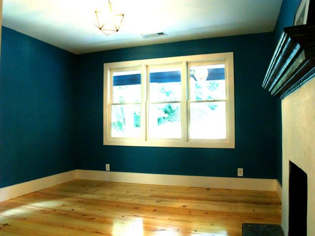 Cette photo montre une chambre d'amis craftsman de taille moyenne avec un mur bleu, parquet clair, une cheminée double-face et un manteau de cheminée en plâtre.