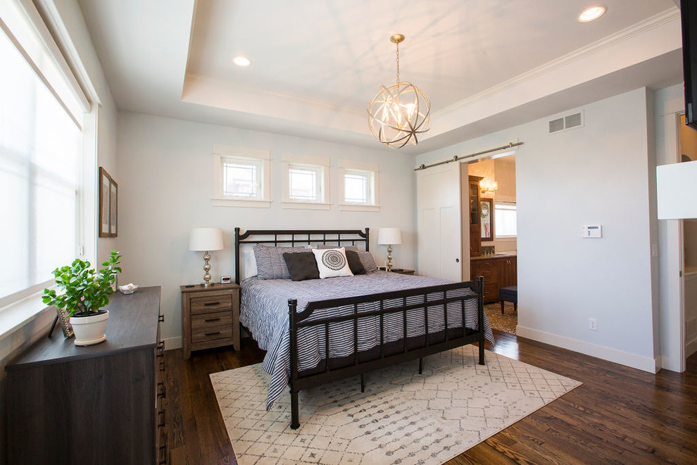 Foto de dormitorio principal de estilo americano grande con paredes grises, suelo de madera en tonos medios, suelo marrón, todas las chimeneas y marco de chimenea de yeso