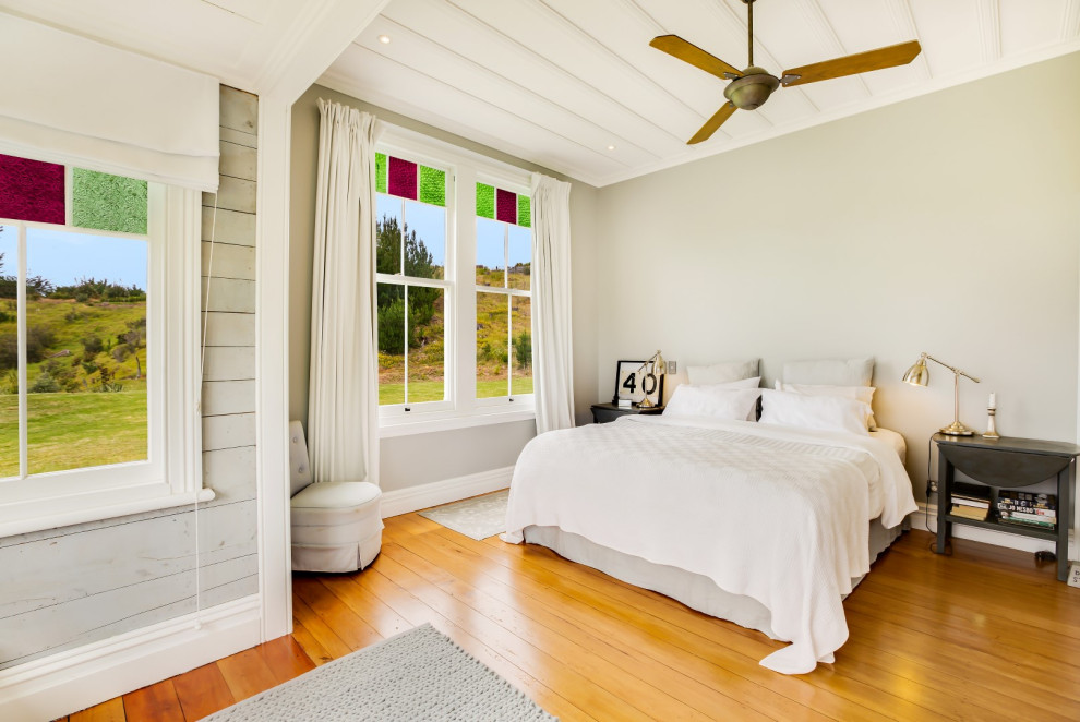 На фото: спальня в стиле кантри с серыми стенами, паркетным полом среднего тона и коричневым полом с