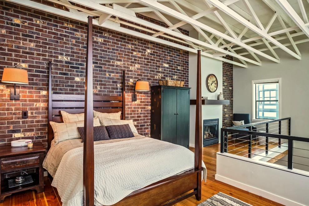 Imagen de dormitorio tipo loft tradicional renovado de tamaño medio con paredes rojas, suelo de madera en tonos medios, todas las chimeneas y marco de chimenea de yeso