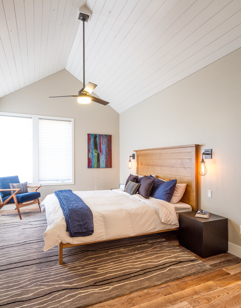 Modelo de dormitorio principal campestre con paredes beige, suelo de madera en tonos medios y suelo marrón