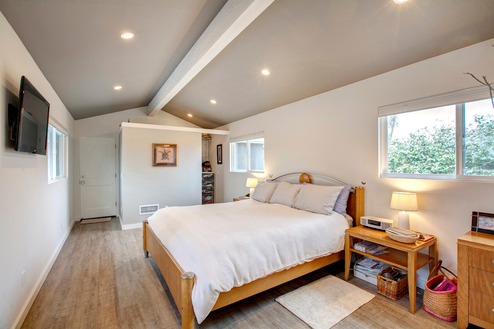 Modelo de dormitorio principal bohemio de tamaño medio con paredes blancas y suelo de madera clara