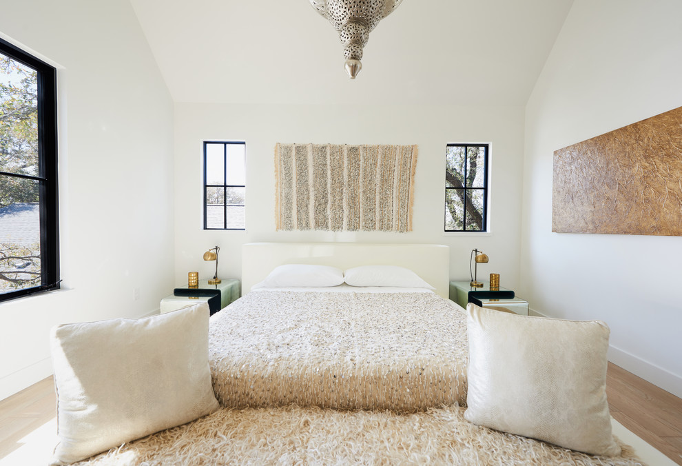 Example of a mid-sized trendy master light wood floor bedroom design in Austin with white walls and no fireplace