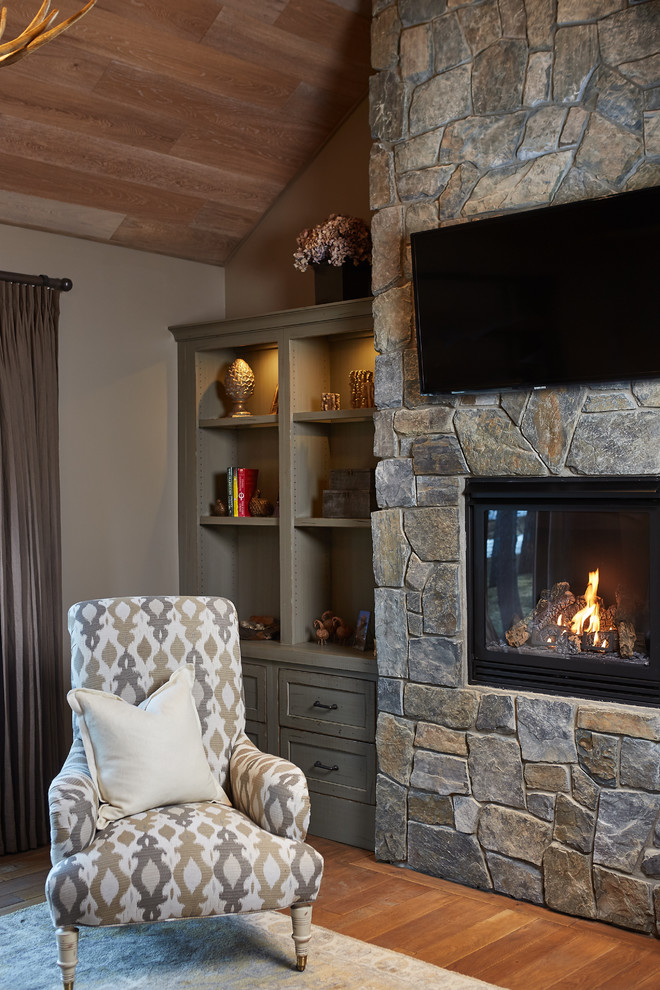 Uriges Hauptschlafzimmer mit beiger Wandfarbe, braunem Holzboden, Kamin und Kaminumrandung aus Stein in Grand Rapids