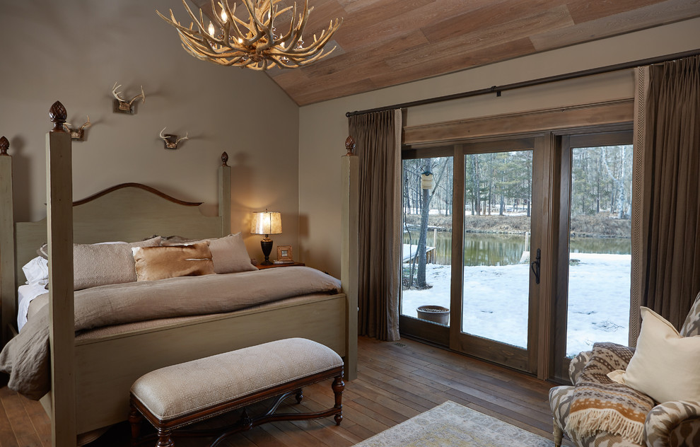 Diseño de dormitorio principal rural con paredes beige y suelo de madera en tonos medios