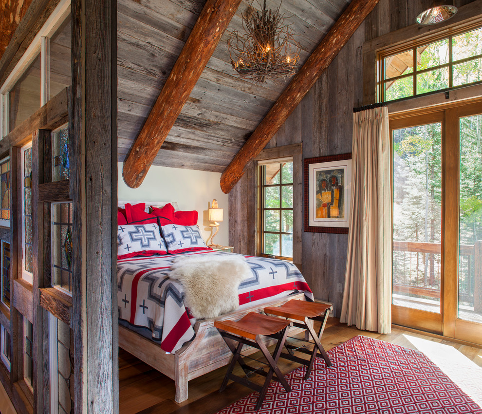 Exemple d'une chambre montagne avec un mur blanc et un sol en bois brun.