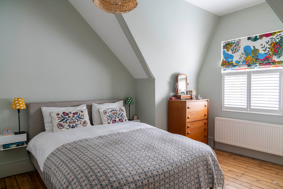 Design ideas for a scandinavian bedroom in London with green walls, medium hardwood flooring and brown floors.