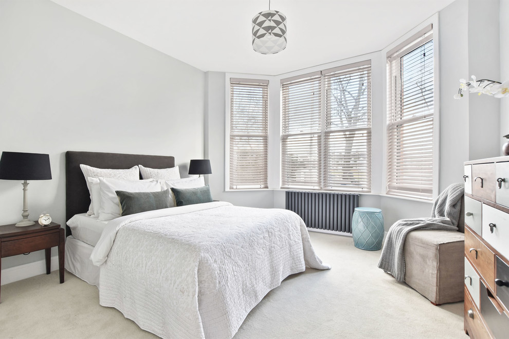 Photo of a bedroom in London with grey walls, carpet and beige floors.