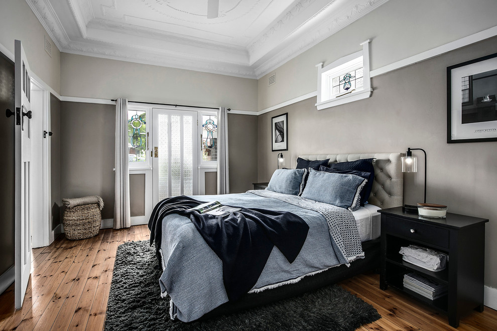 Diseño de dormitorio principal actual de tamaño medio con suelo de madera en tonos medios, suelo marrón y paredes grises