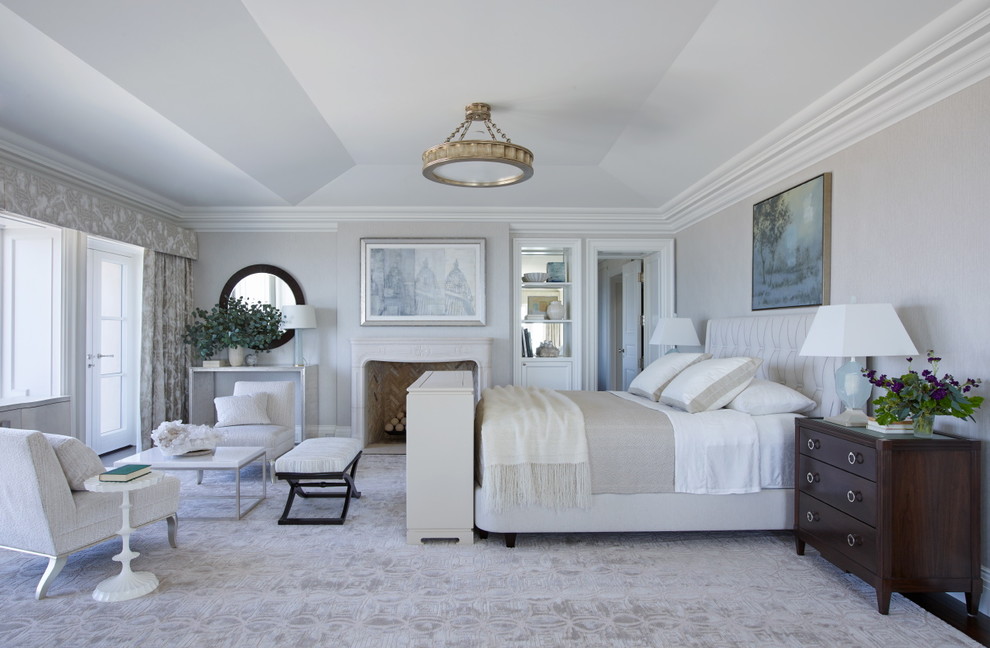 Imagen de dormitorio principal mediterráneo grande con paredes blancas, suelo de madera en tonos medios, todas las chimeneas y marco de chimenea de piedra