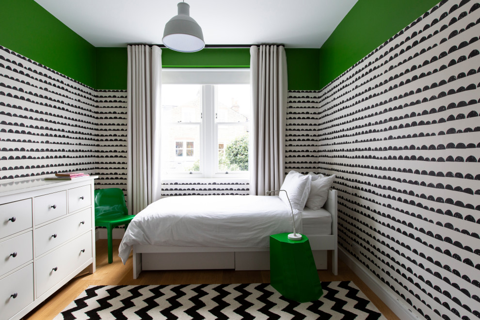 This is an example of a medium sized contemporary guest bedroom in London with green walls, light hardwood flooring and wallpapered walls.