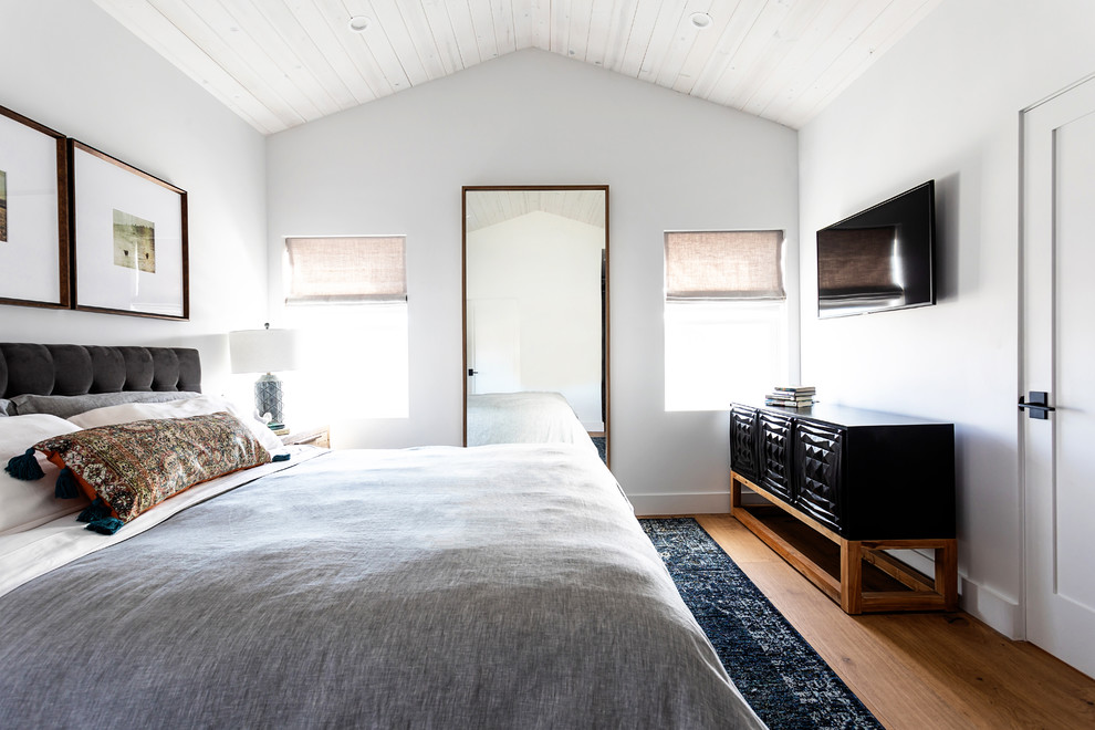 Cette photo montre une chambre chic avec un mur blanc, un sol en bois brun et un sol marron.