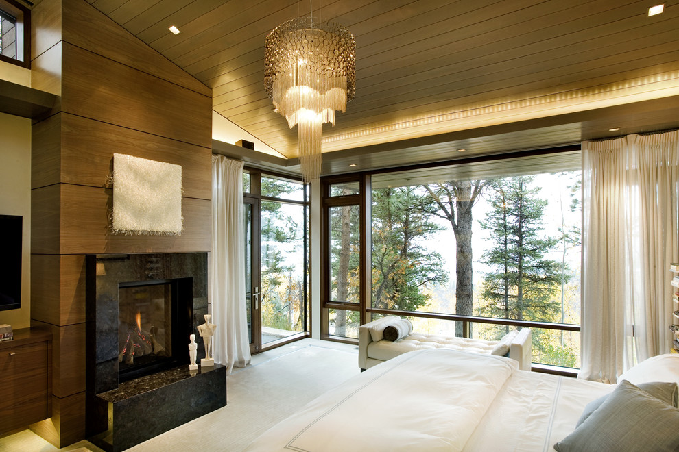 This is an example of a large contemporary master bedroom in Denver with brown walls, a standard fireplace, a stone fireplace surround and carpet.