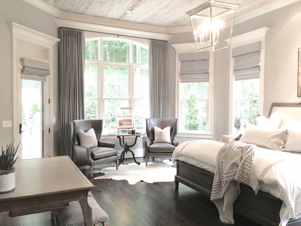 Modelo de dormitorio principal clásico grande sin chimenea con paredes grises, suelo de madera oscura y suelo marrón