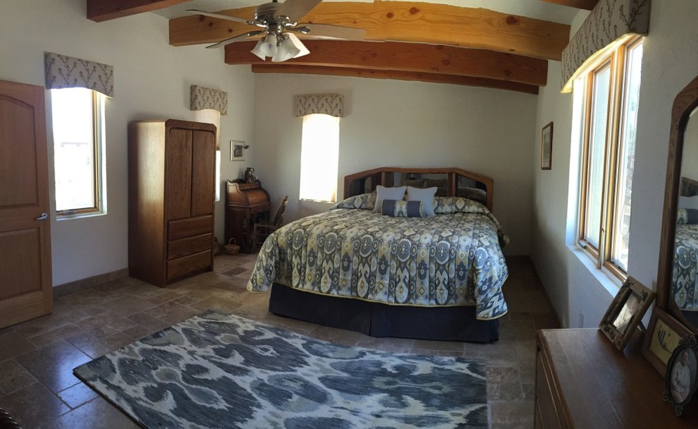 Imagen de dormitorio principal de estilo americano con paredes beige y suelo de travertino