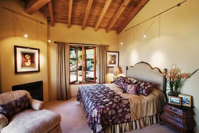 Imagen de dormitorio principal rústico de tamaño medio con paredes beige, moqueta, todas las chimeneas y marco de chimenea de metal