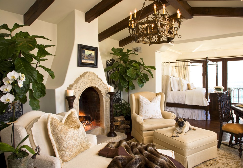 Tuscan master bedroom photo in San Diego with white walls and a plaster fireplace